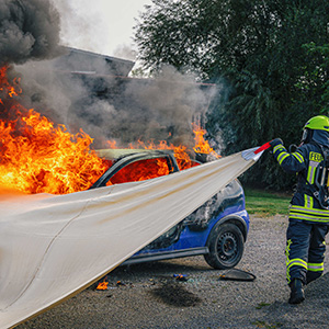 Jutec Brandbegrenzungsdecke wird über brennendes Auto gezogen