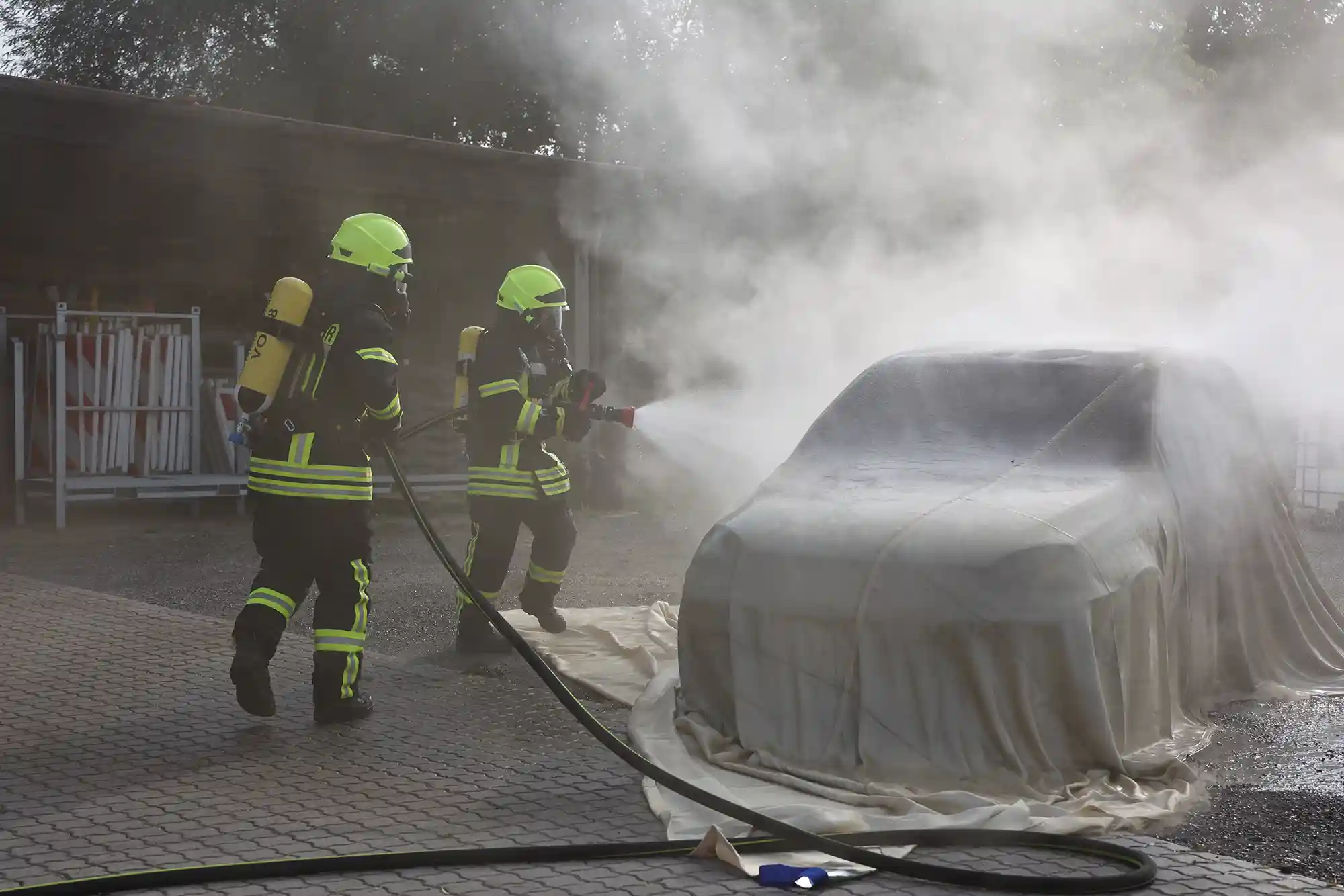 Feuerwehr besprüht Brandbegrenzungsdecke mit Löschwasser. Sie lässt brennbare Batteriegase entweichen